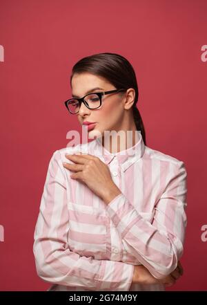 Kluge junge Frau in Brille auf rotem Hintergrund Stockfoto