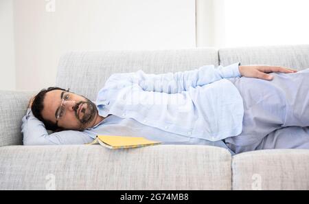 Mann mittleren Alters, der sich auf seinem Sofa ausruhte Stockfoto