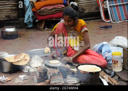 Mumbai; Maharashtra; Indien- Asien; Jan; 2017: Obdachlose indische, arme Stammesfrau, die auf dem Fußweg lebt und Brot oder Chapati auf dem Fußweg Kalbadavi kocht Stockfoto