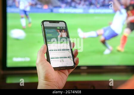 Sehen Sie sich Fußballspiele im Fernsehen an und wetten Sie über die App des Buchmachers über das Mobiltelefon. Nahaufnahme. Stockfoto