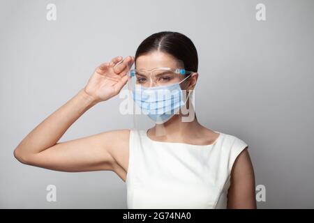 Junge Frau mit Gesichtsschutz und Maske. Coronavirus-Pandemie. Stockfoto