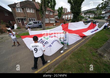 Anwohner tragen eine offizielle Flagge des riesigen England Nationwide Respect-Wahlkampfes von Neeld Crescent in Brent, wo Raheem Sterling aufgewachsen ist, bis zum Wembley-Stadion, bevor die englische Fußballmannschaft beim UEFA Euro 2020-Finale spielt. Bilddatum: Sonntag, 11. Juli 2021. Stockfoto