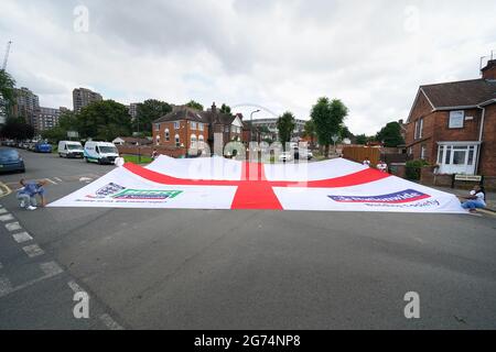 Anwohner tragen eine offizielle Flagge des riesigen England Nationwide Respect-Wahlkampfes von Neeld Crescent in Brent, wo Raheem Sterling aufgewachsen ist, bis zum Wembley-Stadion, bevor die englische Fußballmannschaft beim UEFA Euro 2020-Finale spielt. Bilddatum: Sonntag, 11. Juli 2021. Stockfoto