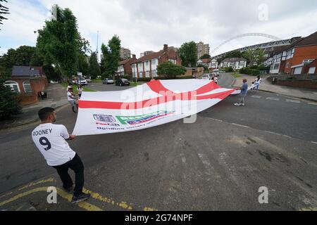 Anwohner tragen eine offizielle Flagge des riesigen England Nationwide Respect-Wahlkampfes von Neeld Crescent in Brent, wo Raheem Sterling aufgewachsen ist, bis zum Wembley-Stadion, bevor die englische Fußballmannschaft beim UEFA Euro 2020-Finale spielt. Bilddatum: Sonntag, 11. Juli 2021. Stockfoto