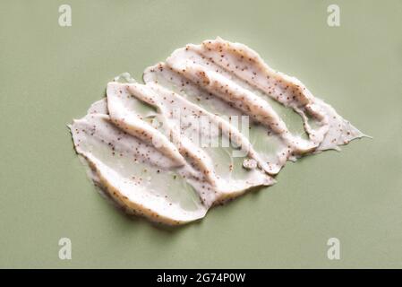 Probe von natürlichem Peeling auf grünem Hintergrund. Peeling-Creme mit Mikrokapseln. Peach- oder Kaffeeschmierabstrich. Stockfoto