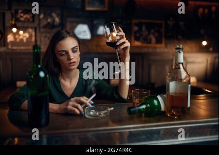 Unglückliche Frau trinkt Alkohol an der Theke in der Bar Stockfoto