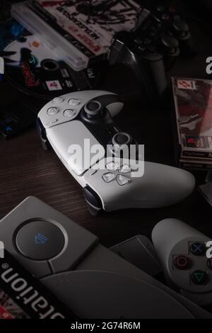 29. Mai 2021, Odessa, Ukraine. Weißer neuer Gamepad-Dualsense für PlayStation 5 auf einem dunklen Hintergrund zwischen Spielen und Konsolen vergangener Generationen. Cybersport Stockfoto