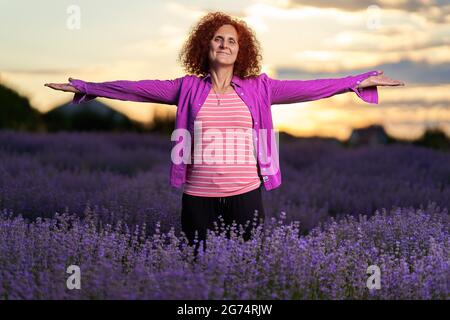 Bäuerin, die bei Sonnenuntergang in ihrem Lavendelfeld steht Stockfoto