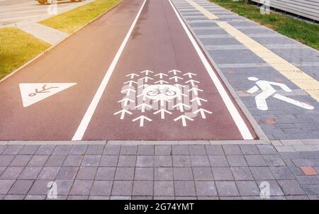 Radweg, Laufstrecke und ein Gehweg. Radweg mit Schildern und Pfeilen auf rotem Asphalt markiert Stockfoto