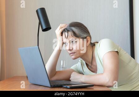 Frau mittleren Alters langweilen sich bei der Arbeit von zu Hause aus Stockfoto