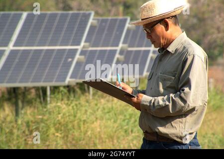 Männlicher Ingenieur mit Notizbuch und Arbeitsbericht zur Inspektion des Solarsystems. Im Freien. Konzept der Energietechnik-Industrie. Stockfoto