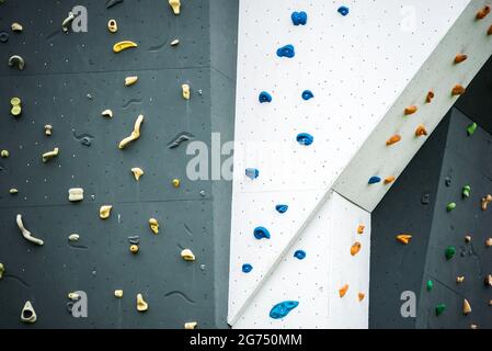 Abstrakte bunte Felswand mit Zehen und Hand halten Nieten., verschiedene Griffe im Outdoor-Fitness-Studio Adventure Park. Stockfoto