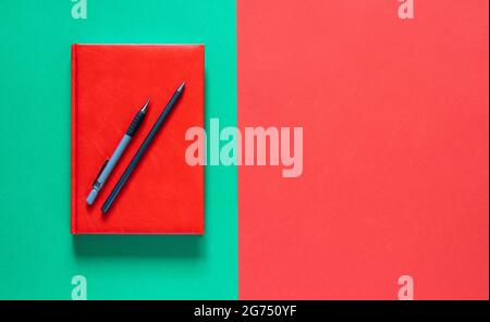 Zurück zum Schulkonzept. Roter Notizblock mit Bleistiften. Grüner und roter Hintergrund. Flach liegend mit Kopierplatz. Stockfoto
