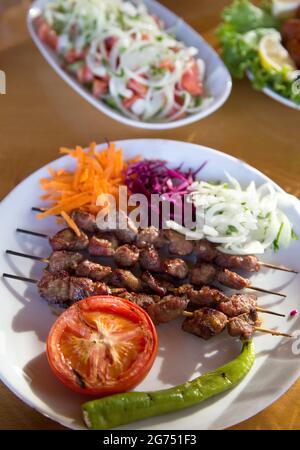 Nahaufnahme des Salats mit gebratenen Hähnchenspießen auf weißem Teller Stockfoto