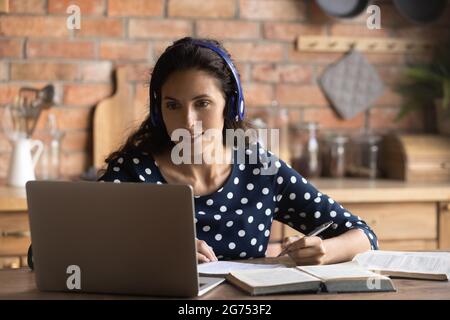 Fröhliche, fokussierte Studentin mit Kopfhörern und Laptop Stockfoto