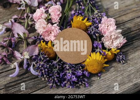 Sommer Kräuter Schreibwaren Stillleben Szene. Unbeschriftete runde Geschenkanhänger, Etikett auf altem Holztisch Hintergrund. Blumenstrauß von Lavendel, Salbei, Gelb Stockfoto