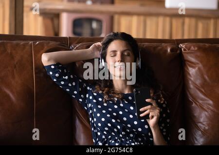 Glückliche, ruhige hispanische Frau, die Pause macht und Lounge-Musik genießt Stockfoto