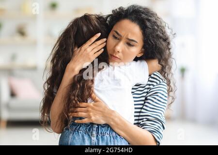 Liebevolle Mutter umarmt ihre weinende kleine Tochter Stockfoto