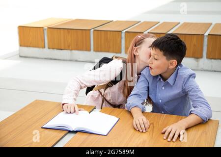 Konzept der ersten Gefühle, ersten Kuss, Schulliebe. Mädchen küsst Junge, Teenager ist sehr glücklich und überrascht, Kindheit Stockfoto