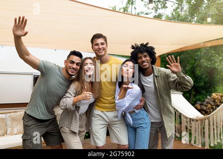 Portrait von glücklichen jungen multirassischen Freunden, die in der Nähe ihres Wohnwagens posieren, lächeln und während der Sommerferien Spaß haben Stockfoto