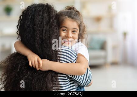 Nettes kleines Mädchen umarmte ihre Mutter und lächelte fröhlich Stockfoto