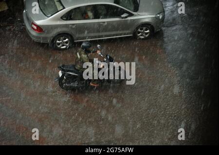 Mumbai; Maharashtra; Indien- Asien; Sep; 2016 : verschwommenes Bild, Luftaufnahme, indischer Mann, der im starken Regen auf dem Fahrrad mit Regenmantel unterwegs ist bombay Stockfoto