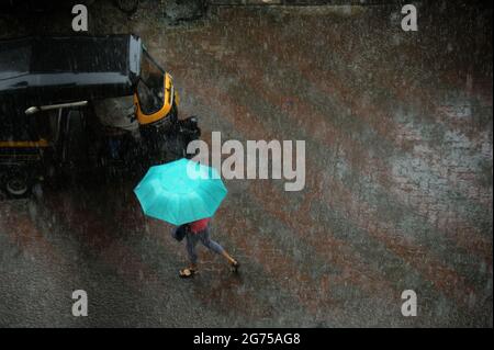 Mumbai; Maharashtra; Indien- Asien; Sep; 2016 : verschwommenes Bild, Junges Mädchen, das bei starkem Regen einen blauen Regenschirm über dem Kopf hält bombay Stockfoto