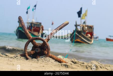 Ein Fischerboot vor Anker am Strand in St. Martin's Island, Bangladesch. Fischerboot rostig traditioneller Anker an einem Strand am Meer. Stockfoto