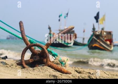 Ein Fischerboot vor Anker am Strand in St. Martin's Island, Bangladesch. Fischerboot rostig traditioneller Anker an einem Strand am Meer. Stockfoto