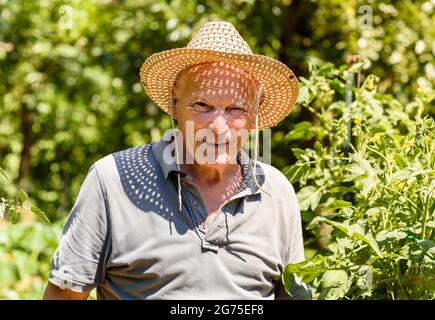 Porträt eines älteren lächelnden Mannes mit Strohhut, der auf die Kamera schaute. Der Lebensstil älterer Menschen. Stockfoto