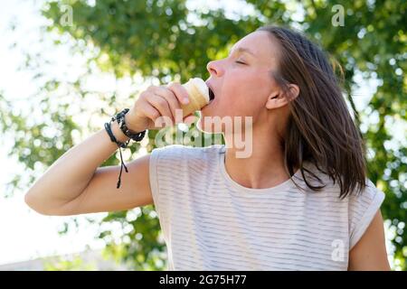 Frau, die an einem heißen Sommertag Eis isst. Sie schloss die Augen und knabbert eifrig an dem erfrischenden, köstlichen Dessert. Stockfoto