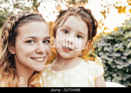 Nettes kleines Rotschopf Mädchen und glückliche junge Mutter mit ähnlichen geflochtenen Frisur umarmt zusammen Stockfoto