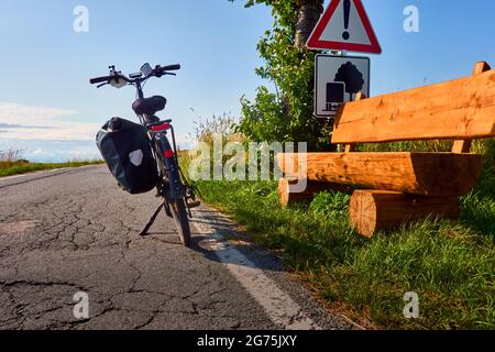 Schwarzes Fahrrad vor einer Sitzbank aus massiven Holzstämmen am Straßenrand in Sachsen, Deutschland Stockfoto