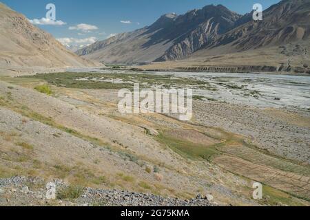 Spiti-Fluss und -Tal, flankiert von hohen Gipfeln und Bergflanken des Himalaya-Gebirges unter blauem Himmel im Sommer in der Nähe von Kaza, Himachal Pradesh, Indien. Stockfoto