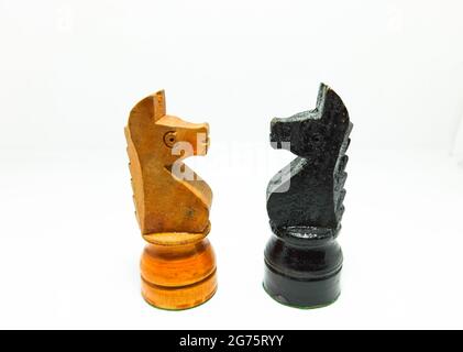 Eine Nahaufnahme von hölzernen Rittern Schachfiguren schwarz und gelb, die auf einem isolierten weißen Hintergrund stehen Stockfoto