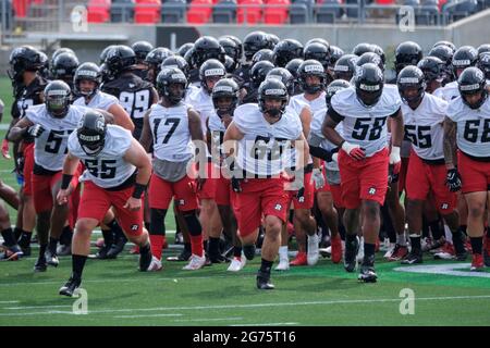 Ottawa, Kanada. Juli 2021. Offensivlineman Nolan McMillan (66) führt die Spieler durch Übungen, als die Ottawa REDBLACKS der Canadian Football League (CFL) ihr Trainingslager auf dem TD-Platz eröffnen, während sie die Saison 2021 eröffnen. Nachdem die CFL die gesamte letzte Saison aufgrund der Pandemie eingestellt hat, wird sie diese Saison gemäß dem genehmigten Protokoll spielen. Kredit: Meanderingemu/Alamy Live Nachrichten Stockfoto