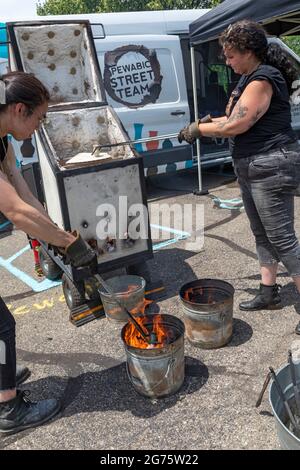 Detroit, Michigan - Mitglieder des Pewabic Pottery Street Teams demonstrieren die japanische Technik des Raku-Feuers von Töpferwaren auf einem Gemeinschaftskunstwerk und einem Mu Stockfoto