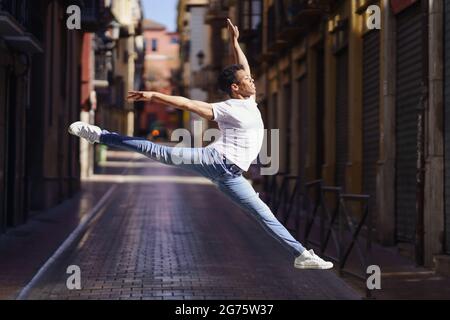 Schwarzer, athletischer Mann, der einen akrobatischen Sprung im Freien macht Stockfoto