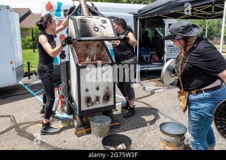 Detroit, Michigan - Mitglieder des Pewabic Pottery Street Teams demonstrieren die japanische Technik des Raku-Feuers von Töpferwaren auf einem Gemeinschaftskunstwerk und einem Mu Stockfoto