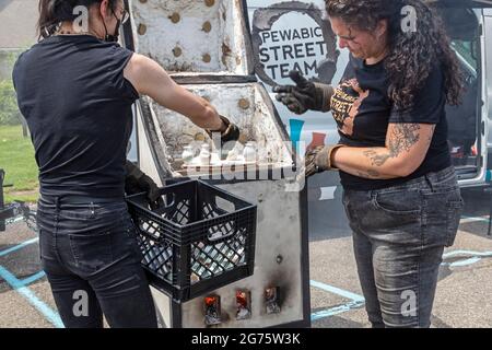 Detroit, Michigan - Mitglieder des Pewabic Pottery Street Teams demonstrieren die japanische Technik des Raku-Feuers von Töpferwaren auf einem Gemeinschaftskunstwerk und einem Mu Stockfoto