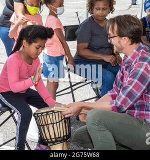 Detroit, Michigan - Kinder lernen auf einem Kunst- und Musikfestival Trommeln. Ben Piper (rechts), Musiklehrer an den Detroit Public Schools, Stockfoto