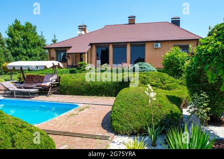 Villa im europäischen Stil mit Pool und Garten mit schön getrimmten Büschen Stockfoto