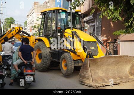 JCB Earth Moving Maschine, die auf einer Straße arbeitet. JCB-Schaufellader repariert einen Abschnitt einer unbefestigten Straße. Im Wohnviertel wächst die Straße. Thema o Stockfoto