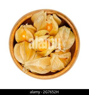 Kap Stachelbeeren mit teilweise offenem Kelch, in einer Holzschale. Frische Früchte von Physalis peruviana, auch golden, inka- und gemahlene Beere, uchuva und poha. Stockfoto