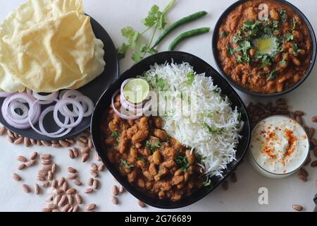 Rote Kidney Beans in einer dicken und würzigen Soße aus Zwiebeln und Tomaten serviert zusammen mit gedämpftem Basmati-Reis und Papad. Allgemein bekannt als rajma masala an Stockfoto