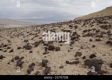 Flint Stone Gesteine oberhalb von Nachal Admon, der Judäischen Wüste, Verdunstungspools südlich des Toten Meeres, dem Rift Valley, den Bergen von Edom und Herbstwolken. Stockfoto