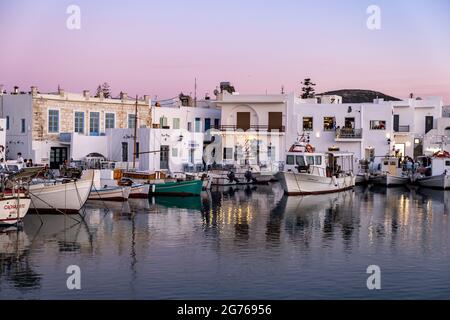 Griechenland, Paros Insel Naousa alten Hafen. Kykladen. 19.Mai 2021. Typische Fischerboote, die am Hafendock festgemacht sind, Menschen in traditionellen Outdoor-Cafés und Stockfoto