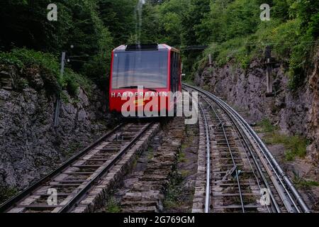 Rote Standseilbahn fährt bergab von Harder Kulm, Top of Interlaken. Die Seilbahn fährt Touristen vom beliebten Aussichtspunkt aus auf und ab. Transportation Stockfoto