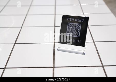 Menü anzeigen und QR-Code-Zeichen auf dem Tisch im Café scannen Stockfoto