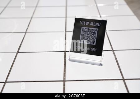 Menü anzeigen und QR-Code-Zeichen auf dem Tisch im Café scannen Stockfoto